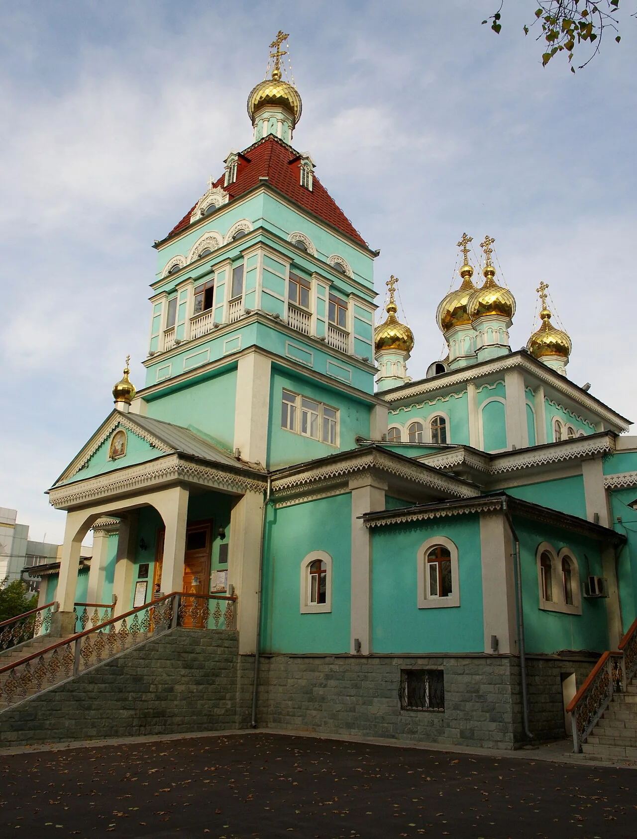 Никольский собор, октябрь 2011: бирюзовые стены, белые наличники, красная шатровая кровля колокольни и золотые купола-луковицы, у крыльца — лестница с узорными перилами. Найдите над входом икону в треугольном фронтоне: она смотрит на улицу, как хозяин, вышедший встретить гостей. Фото: Ken and Nyetta, 2011, Wikimedia Commons, CC BY 2.0
