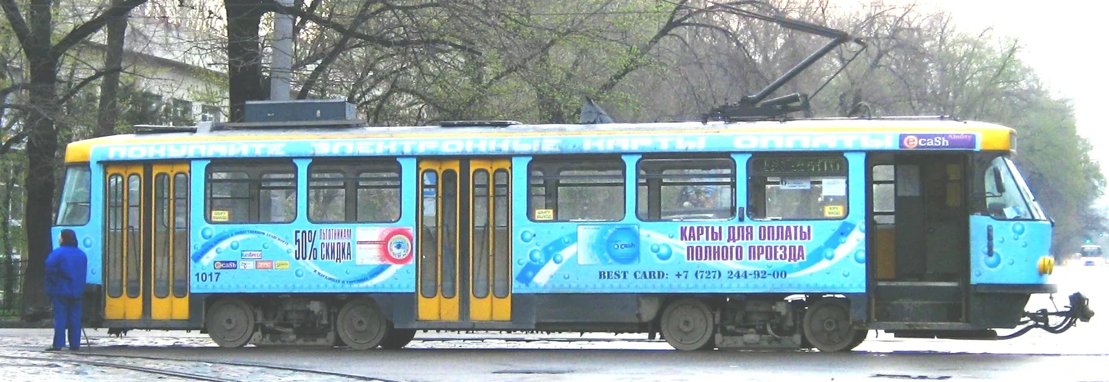 Трамвай Tatra на Толе би, апрель 2009 года: рельсы в асфальте, провода над головой, реклама во весь борт. На прогулке мы ищем это место без вагона. Фото: Ds02006, Wikimedia Commons, общественное достояние