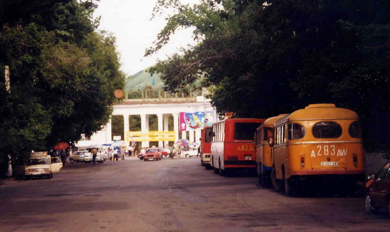 Улица Гоголя в 1999 году: в конце — белая колоннада, у тротуара жёлтые автобусы, над дорогой смыкаются кроны. Автор подписал кадр только как «улица Гоголя», так что колоннаду мы не называем, хотя очень хочется. Фото: Brian Harrington Spier, Wikimedia Commons, CC BY-SA 2.0