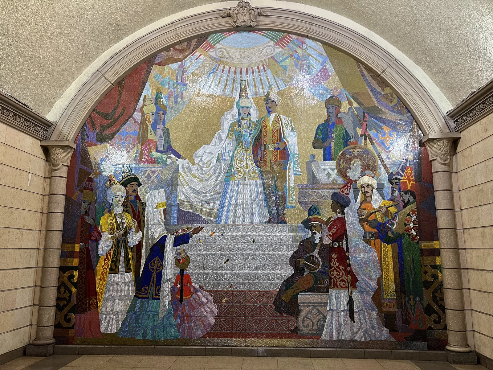 Мозаика в арочной нише: на голубом фоне фигуры в праздничных костюмах, музыканты, всадник, белые одежды, вокруг светлая облицовка. Место кадра в каталоге проекта не подписано. Это квадрат-бонус: мозаика не входит в десять деталей, но если встретите — отметьте на полях. Фото: Валентин Шафранов