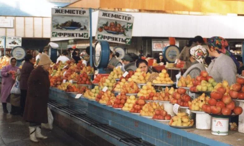 Фруктовые ряды алматинского рынка, 2001 год: яблоки, груши, над прилавками вывеска «Жемістер — Фрукты». Фото: Brian Harrington Spier, Wikimedia Commons, лицензия CC BY-SA 2.0. Временная обложка до своего кадра