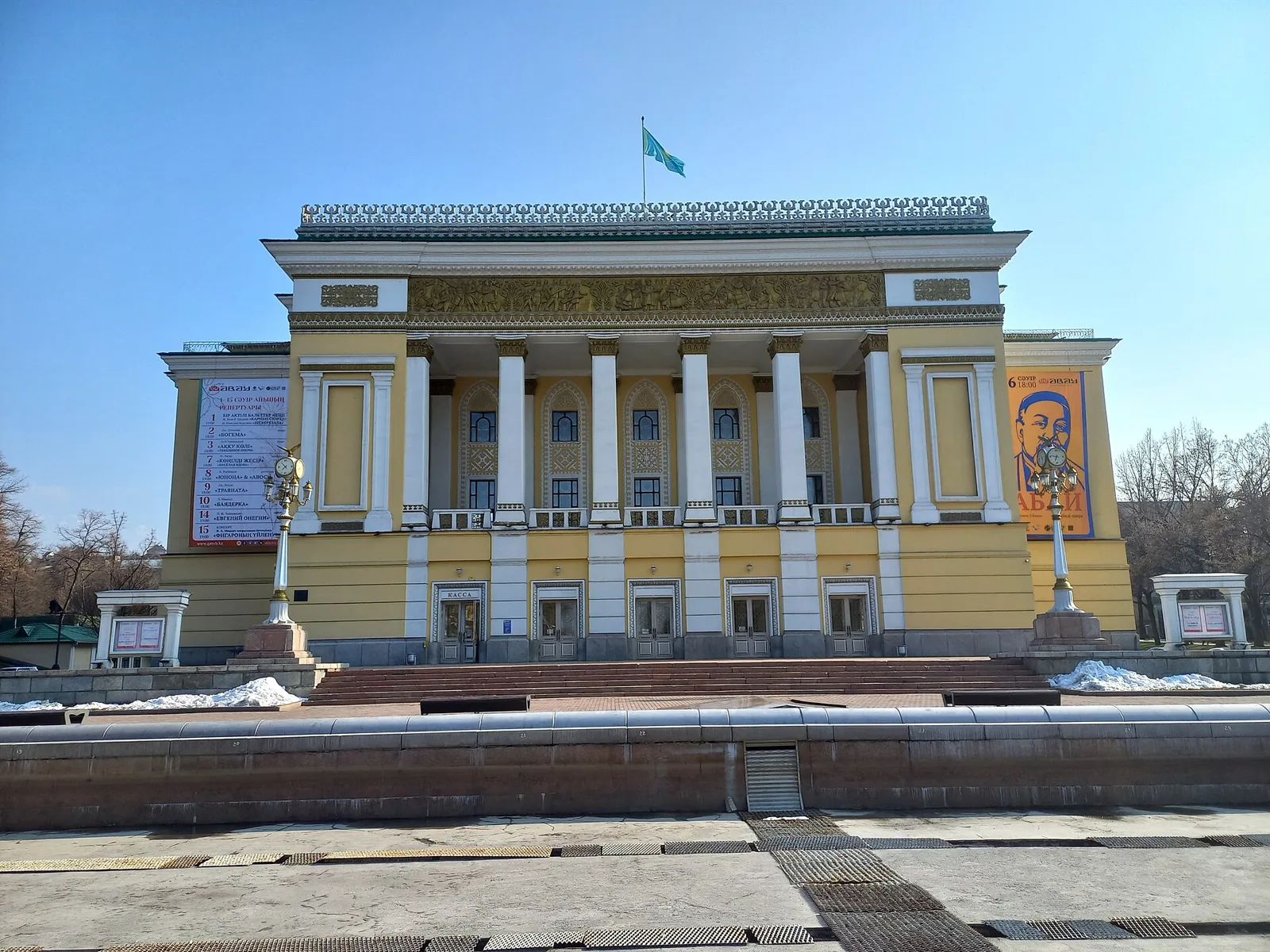 Казахский национальный театр оперы и балета имени Абая, 25 марта 2022 года: колоннада, рельефный фриз и остатки снега у сухого весеннего фонтана. Фото: DS28, лицензия CC BY-SA 4.0, Wikimedia Commons. Временная обложка до своего кадра